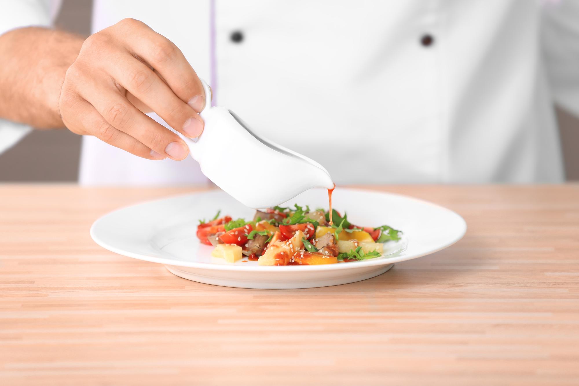Chef arranges plated tasting menu on wooden table